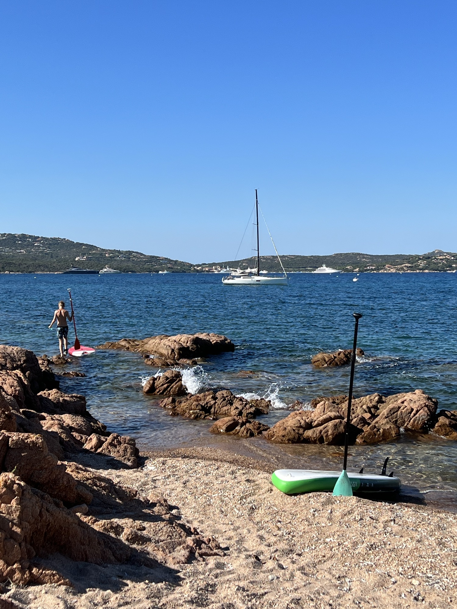 Arthur et les paddles sur la plage devant le Pogo 12.50 Purple Rain - Sardaigne - 2022