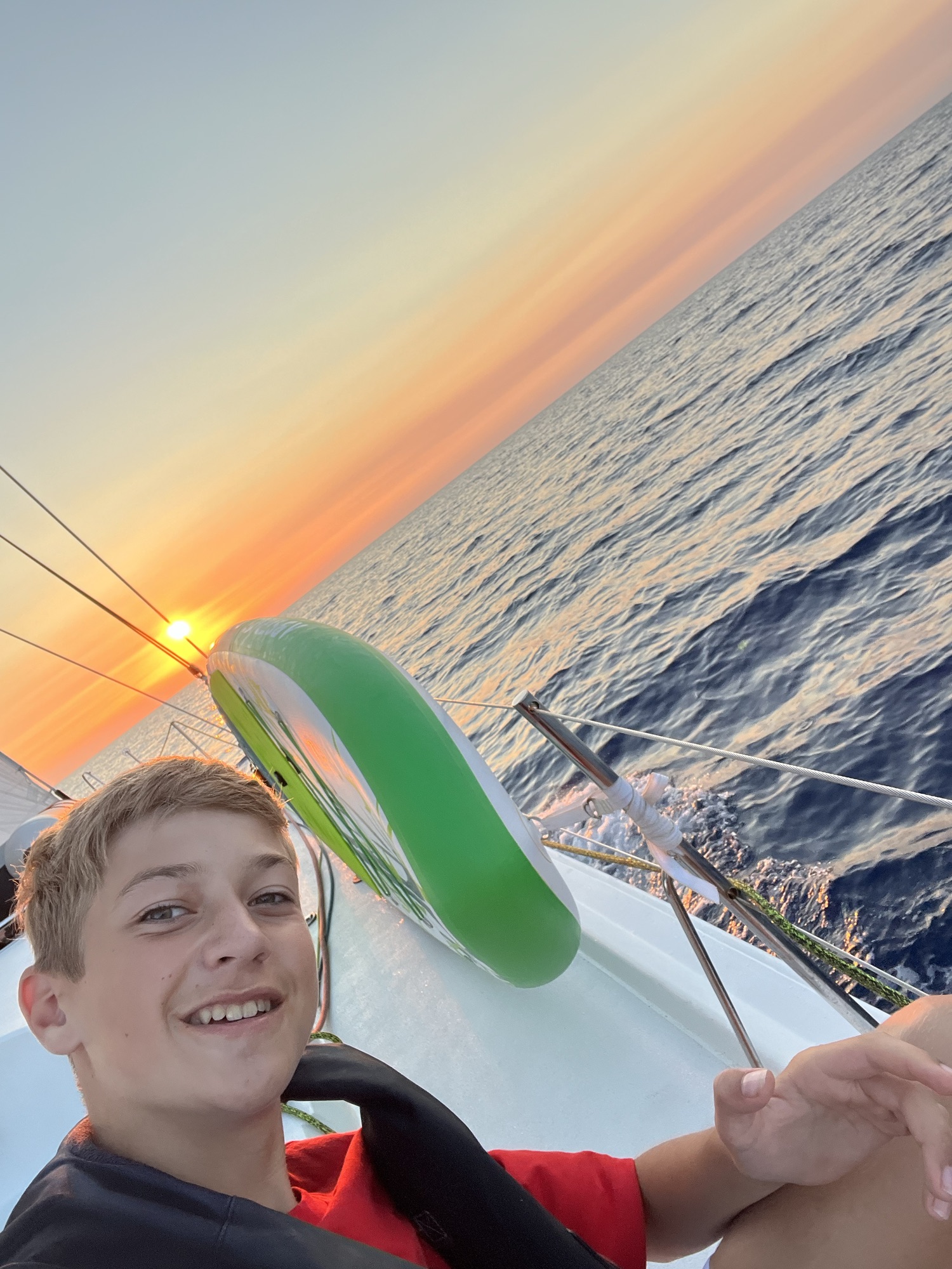 Arthur devant le coucher du soleil sur le pogo 12.50 Purple Rain - traversée Sardaigne-Layet - 2022