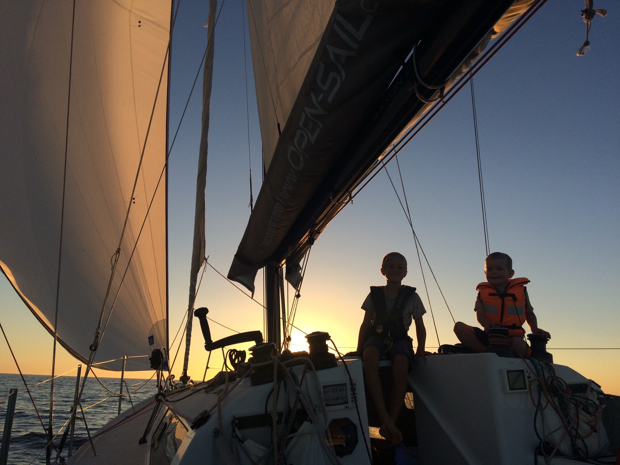 Deux garçons sur le rouf du Pogo 30 sous gennaker au soleil couchant